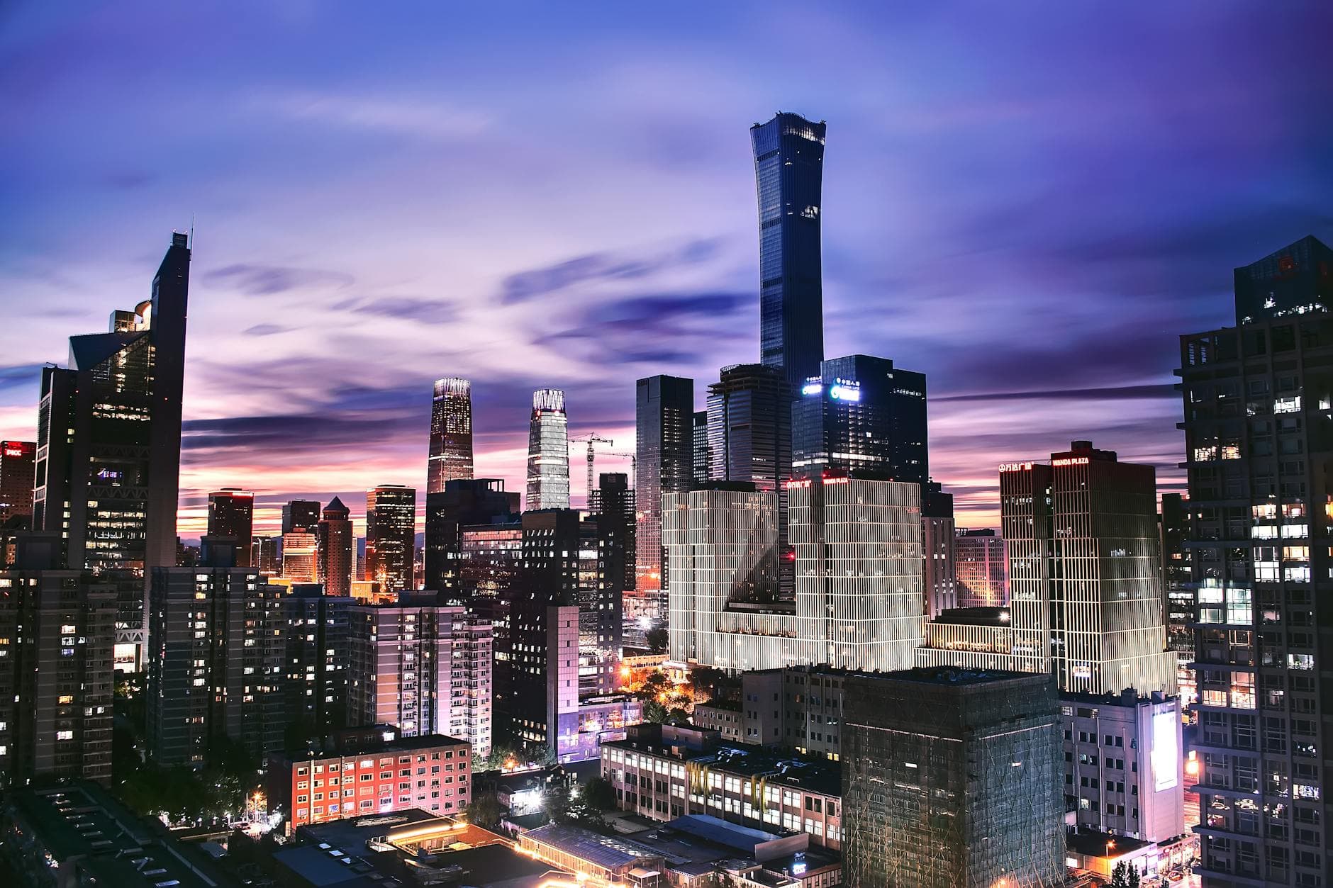 Explore the vibrant skyline of Beijing as twilight paints the horizon in this stunning aerial shot.