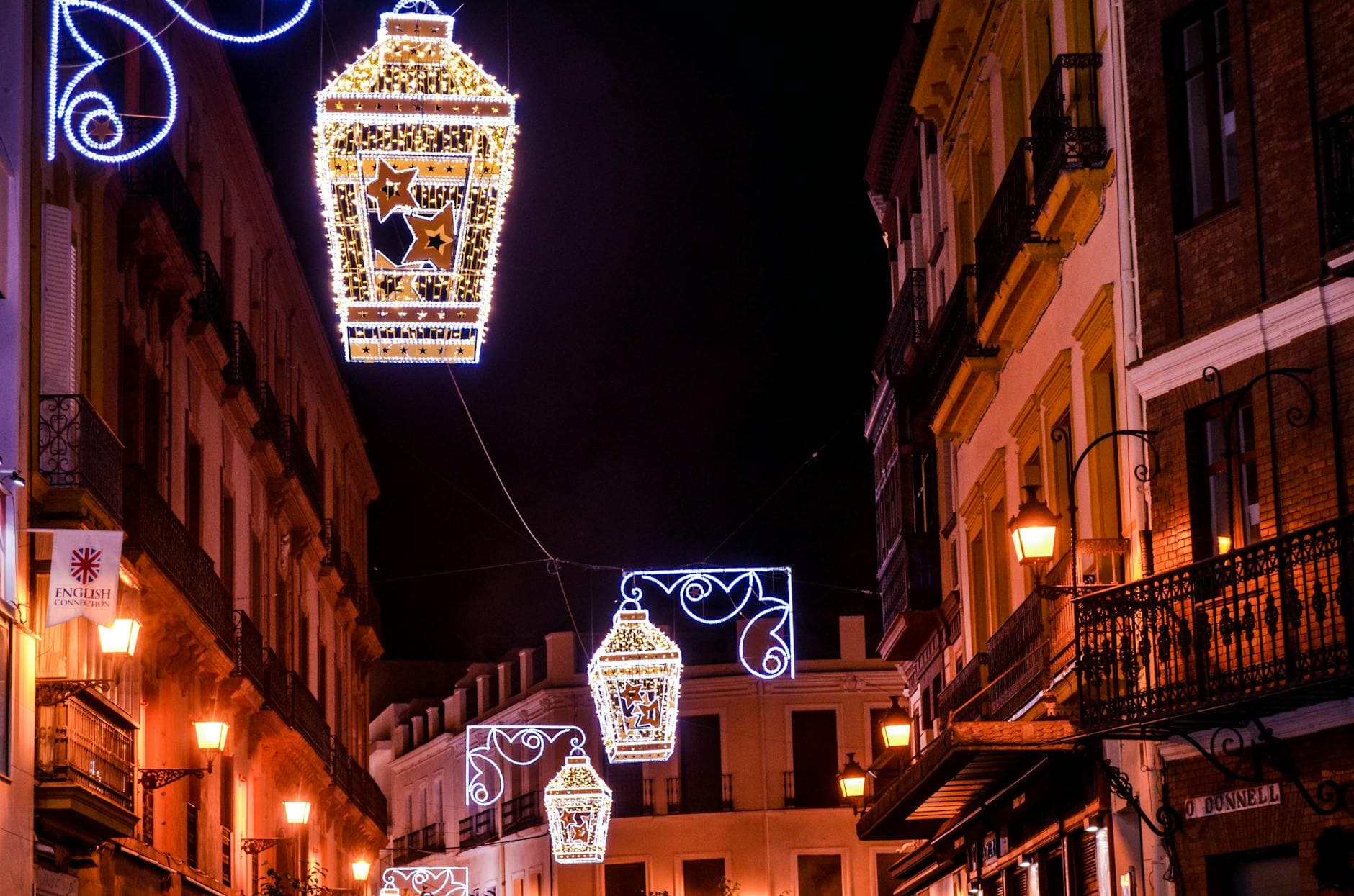 Vibrant street lanterns illuminate a historic street in Seville, creating an enchanting evening atmosphere.