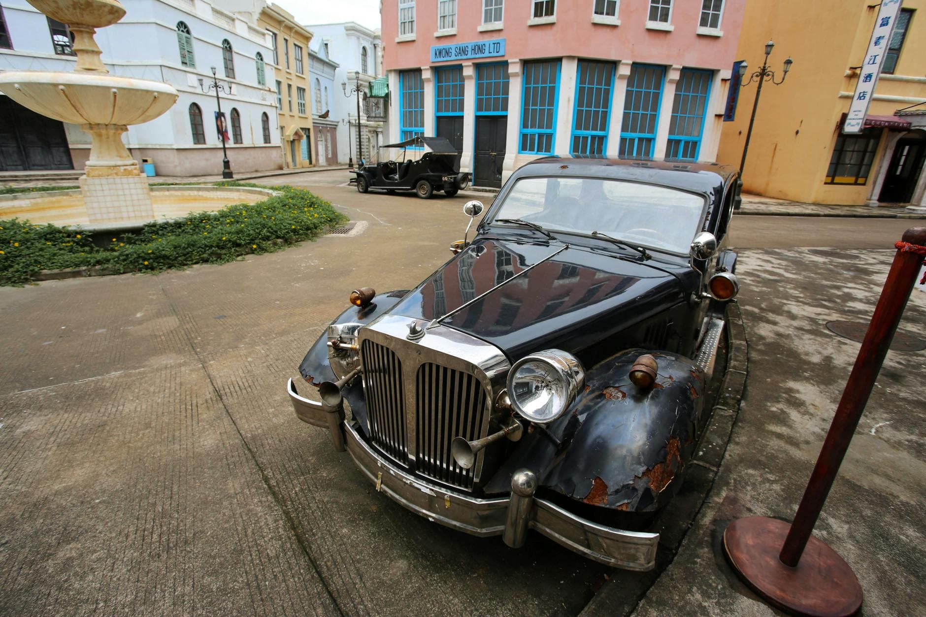 Old classic car parked on a vintage street with historic buildings in the background.