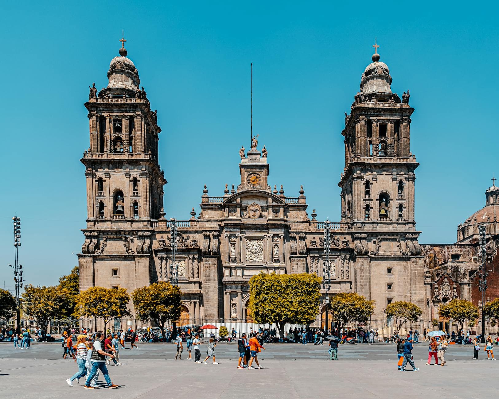 Stunning view of the Metropolitan Cathedral in Mexico City with clear blue skies and bustling activity.