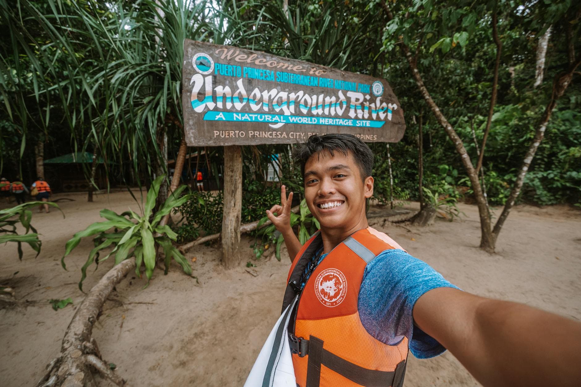 Young man taking a selfie at Puerto Princesa Underground River sign in Palawan, Philippines.