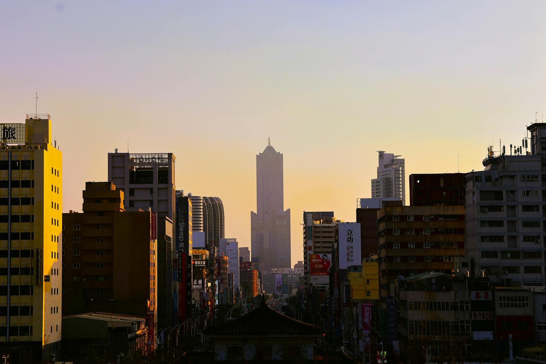 Twilight view of Kaohsiung city skyline featuring tall buildings and a sunset ambiance.